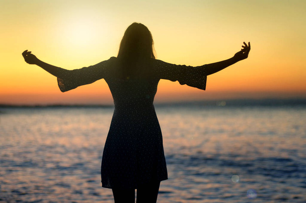 Femme encourageante bras ouverts au lever du soleil en mer
 - Photo, image