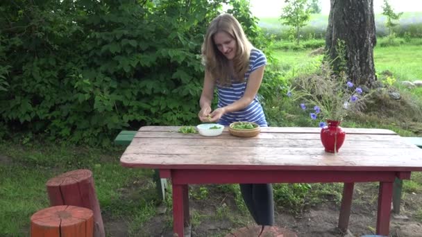 mulher vegetariana feliz mãos casca ervilhas verdes frescos na mesa de madeira vermelha. 4K
 - Filmagem, Vídeo