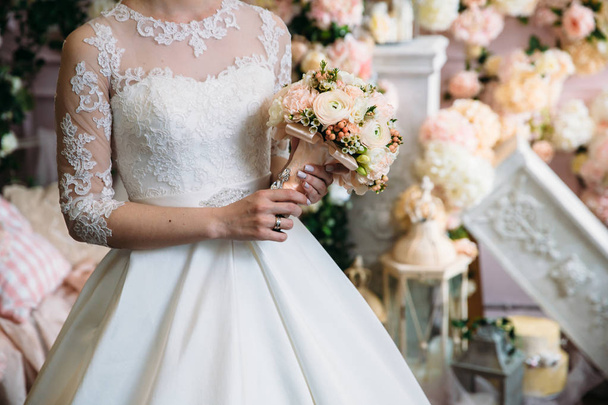 Closeup of bride hands holding beautiful wedding bouquet with white and pink roses. Concept of floristics - 写真・画像