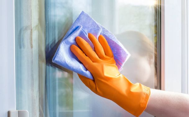 Ένας εργαζόμενος σκουπίζει το παράθυρο με . - Φωτογραφία, εικόνα