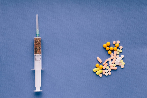 Fecskendőt és gyógynövény tabletták kék háttérrel - Fotó, kép