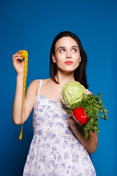 beautiful sweet girl in a simple dress holding a cabbage and centimeter - Zdjęcie, obraz