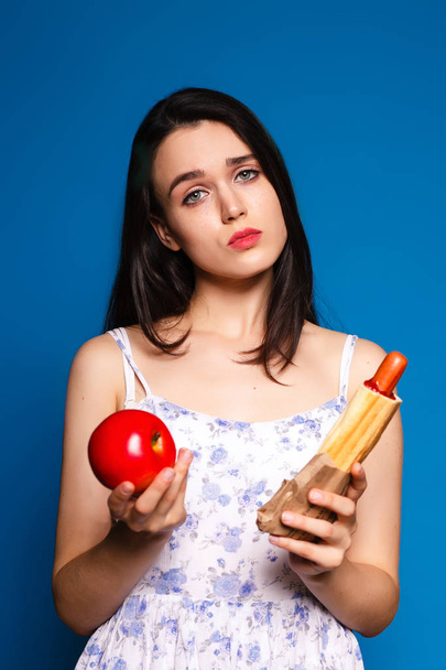 difficult choice of food, a beautiful brunette with Vegetables and hotdog - 写真・画像