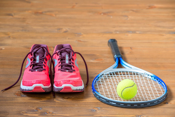 Набір для гри в теніс кросівки, ракетка і м'яч на підлозі
 - Фото, зображення