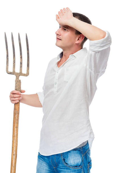 Bauer im weißen Hemd mit einer Mistgabel in der Hand wischt die  - Foto, Bild