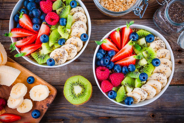 Breakfast bowl: granola with banana, kiwi, raspberry, strawberry, blueberry and chia seeds - Photo, Image