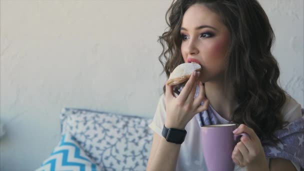 Szép nő, enni a cookie-kat és inni a kávét a szobájában az ágyban. - Felvétel, videó