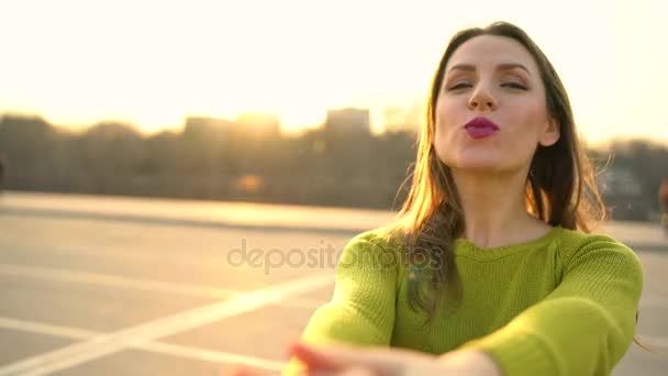 Kövessen - boldog, fiatal nő húzás srácok kezét, és küld egy légi csók - kéz a kézben sétált egy ragyogó napsütéses napon - Felvétel, videó