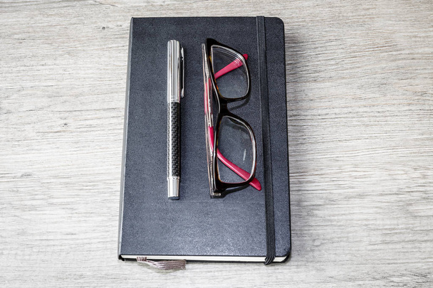 suministro de oficina - gafas, pluma, cuaderno, mesa de madera
 - Foto, Imagen