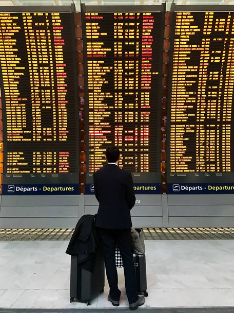 Homme d'affaires avec une mallette sur fond de tableau de départ à l'aéroport
 - Photo, image