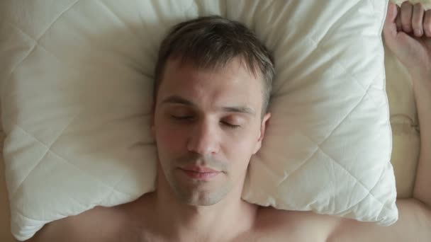 A man sleeps on the bed with a restless sleep. Sharply opens his eyes, looks into the camera and screams in fright. Close-up. View from above - Footage, Video