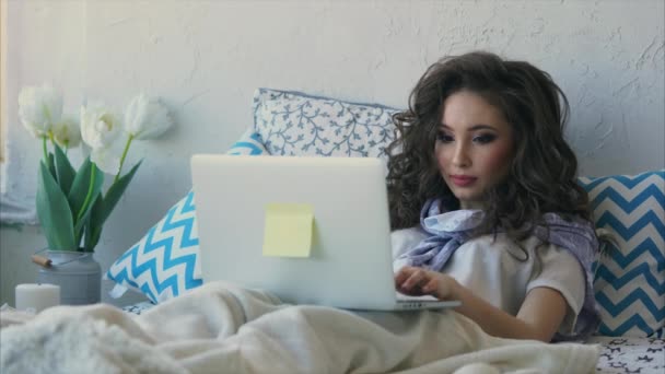 Giovane bella donna freelance che lavora con il suo computer portatile a casa in camera da letto
. - Filmati, video