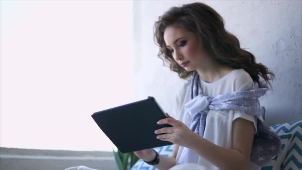 Ładna kobieta utworów w Internecie na tablecie w salonie za pomocą wifi. - Materiał filmowy, wideo