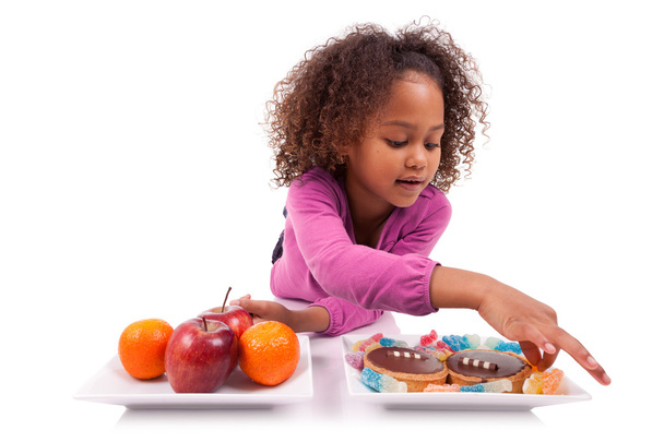 Little African Asian girl hesitating between fruits or candy - Photo, Image