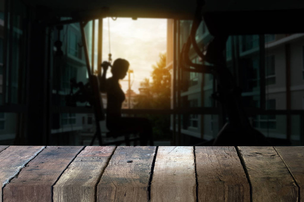 Prázdné horní dřevěný stůl a rozostření fitness mladá žena provést něj - Fotografie, Obrázek