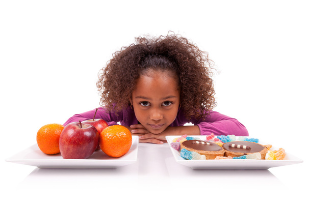 Little African Asian girl hesitating between fruits or candy - Fotoğraf, Görsel