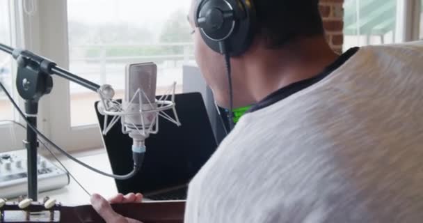 černoch kreativní hudebník v domácím studiu pracuje hrát, zpívat a zaznamenáním kytara s notebook tablet a vnitřní mikrofon v moderní průmyslové domě. 4k kapesní zpět video natočené - Záběry, video