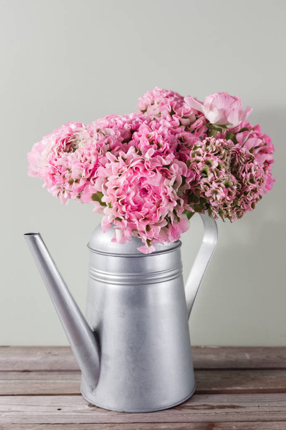 pink persian buttercup flowers. Curly peony ranunculus in Metallic gray vintage watering can, copy space. - Fotó, kép