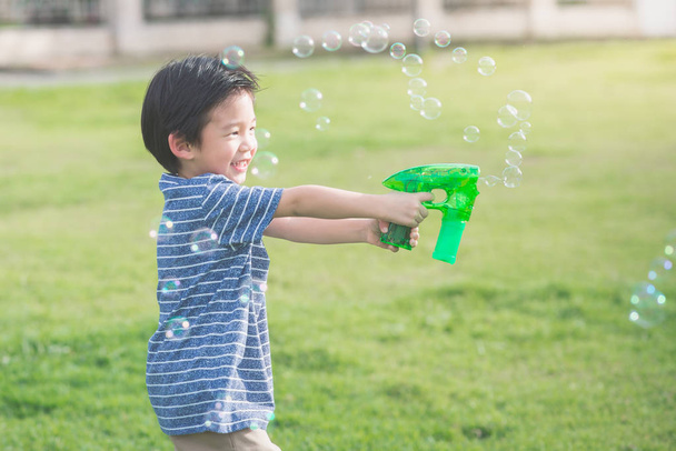 Asian child Shooting Bubbles from Bubble Gun  - Foto, imagen