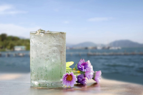 lasillinen vettä ja väärennös kukka puupöydälle merinäköalalla backgro
 - Valokuva, kuva