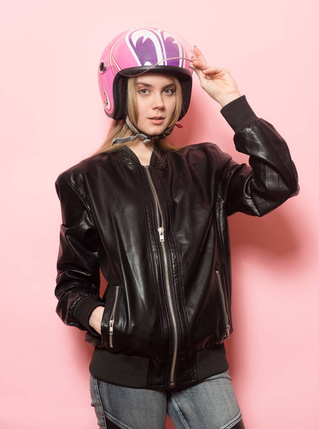 Biker girl wearing black leather jacket and pink motorcycle helmet. - Fotó, kép