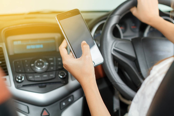 Las mujeres asiáticas están conduciendo coches y utilizando un teléfono inteligente en la carretera
. - Foto, Imagen