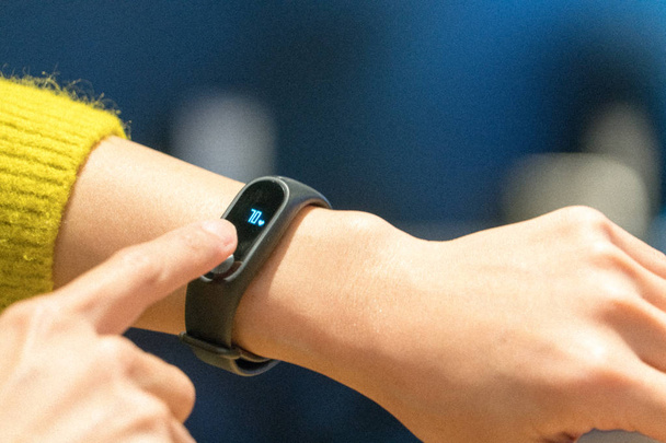 Women touching fitness smart band on her hand - Photo, Image