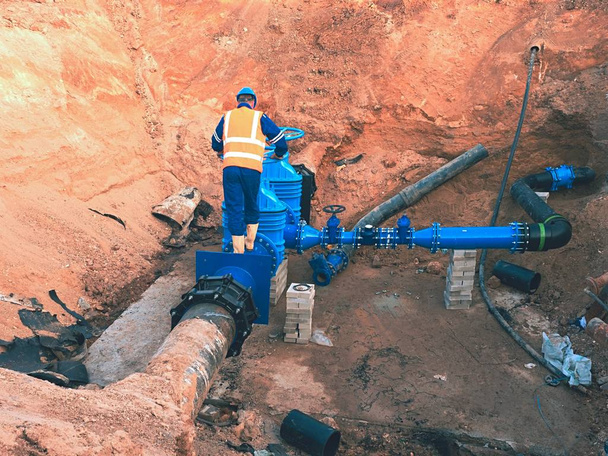 Werknemer in veiligheid kleding rijden ventiel conduit op stad drinkbaar water pipe  - Foto, afbeelding