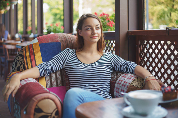 Молодая женщина сидит в помещении в городском кафе
 - Фото, изображение