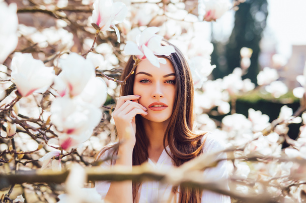 美しい女性の肖像画は春にピンクのモクレンの美しい庭園でリラックスします。 - 写真・画像
