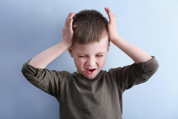 Little boy suffering from headache on color background - Foto, imagen