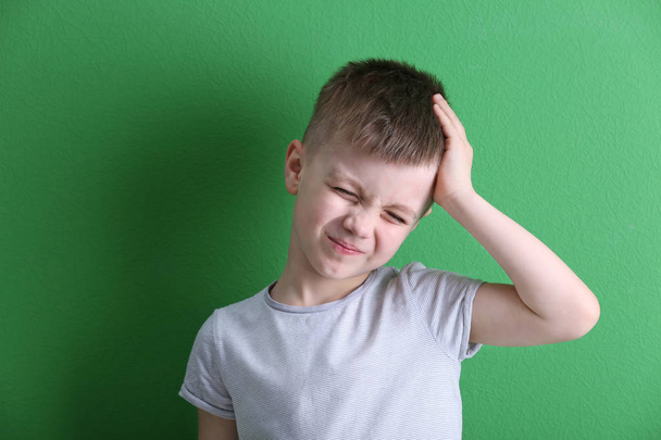 Little boy suffering from headache on color background - Photo, Image