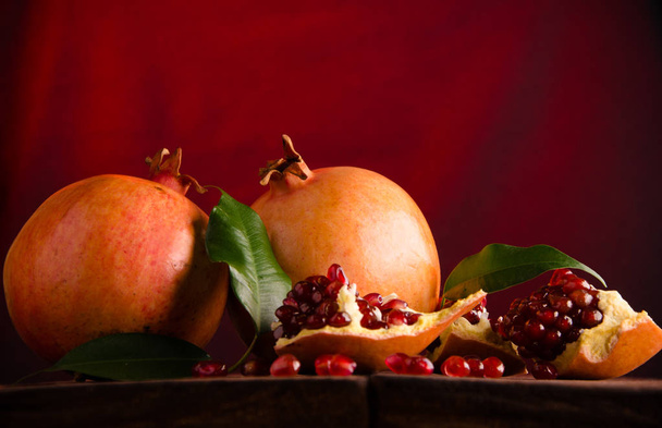 the pomegranate is ripe. cut into pieces of ripe pomegranate. on wooden boards. - Zdjęcie, obraz