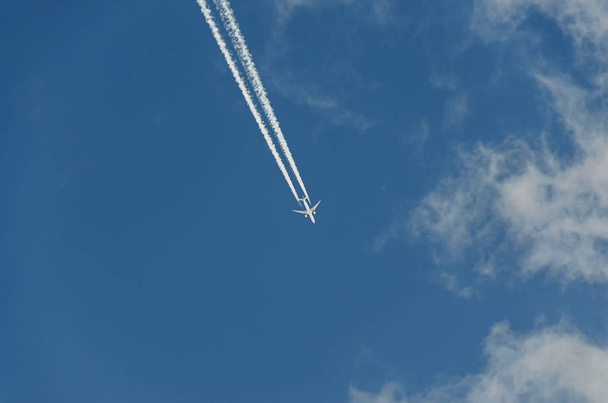 Αεροπλάνο με αντίδραση μονοπάτι που πετούν πάνω από το γαλάζιο του ουρανού με σύννεφα - Φωτογραφία, εικόνα