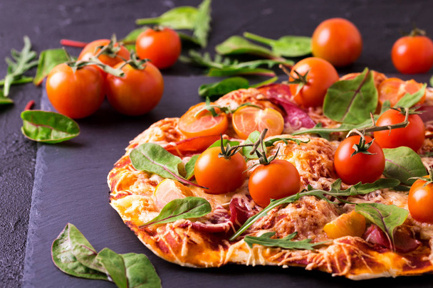 Pizza fatta in casa con pancetta, pomodori, spinaci, rucola e formaggio
 - Foto, immagini