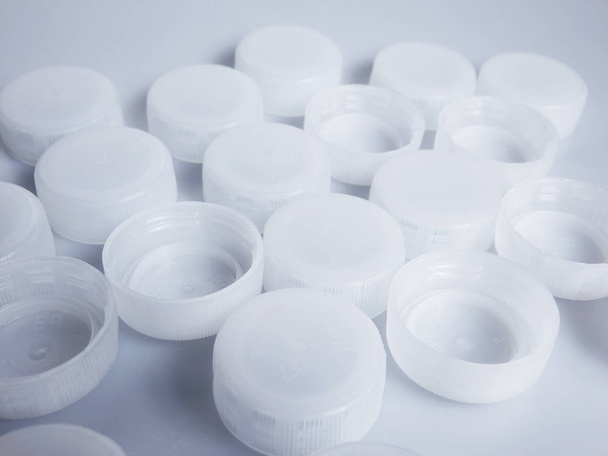 set of white plastic bottles caps on white paper background - Foto, Imagem