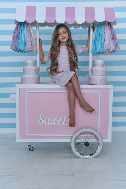 little girl sitting on candy cart - 写真・画像