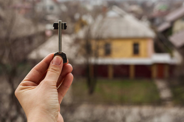 Nahaufnahme Hand mit Schlüssel im Hintergrund des Hauses. - Foto, Bild