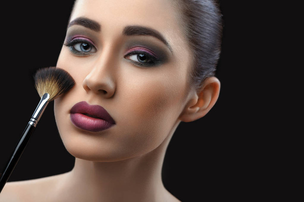 Young beautiful woman wearing professional makeup holding makeup - Фото, изображение