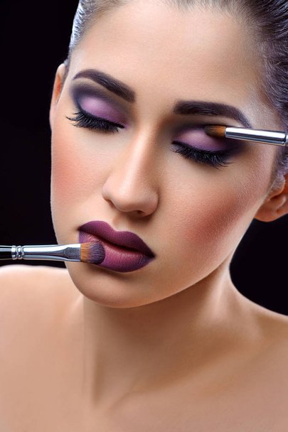 Young beautiful woman wearing professional makeup holding makeup - Foto, imagen