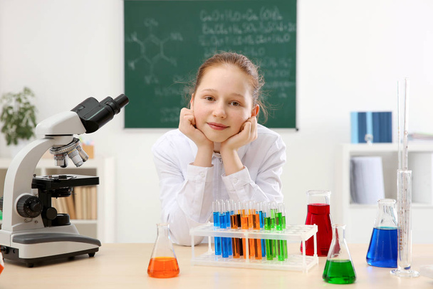 schönes Schulmädchen sitzt am Tisch im Chemieunterricht - Foto, Bild