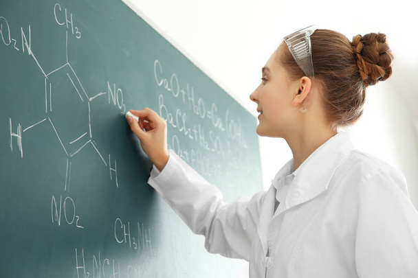 Beautiful school girl standing at chalkboard in chemistry class - Valokuva, kuva