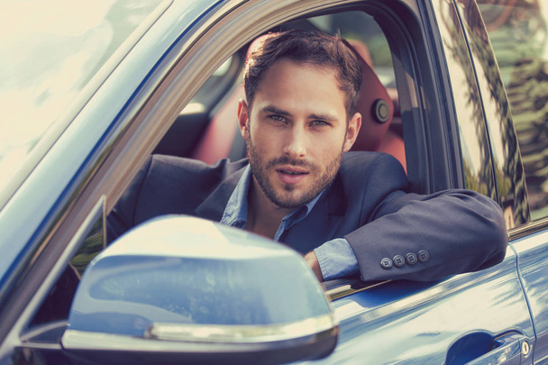 Szczęśliwy człowiek kupujący siedzi w jego nowy samochód gotowy do podróży.  - Zdjęcie, obraz