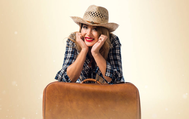 Sexy donna bionda cowgirl con valigia vintage su retro ocra
 - Foto, immagini