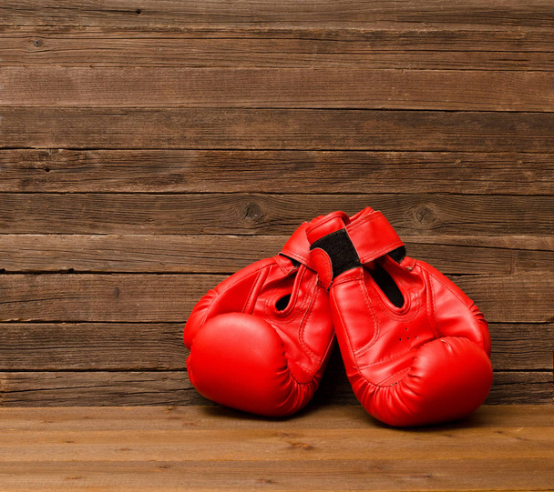 Two red boxing gloves on a wooden brown background, empty space - Photo, Image