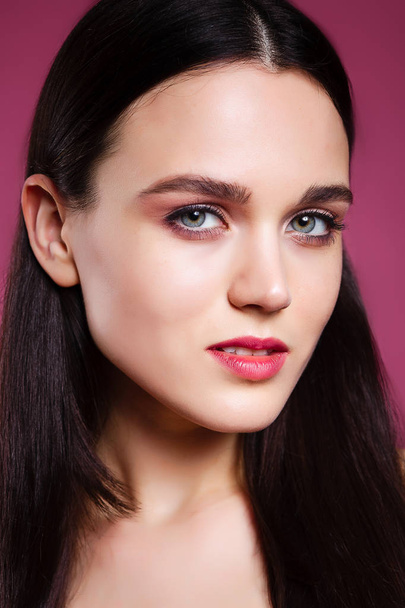beautiful young brunette woman on a pink background in the studio - Fotoğraf, Görsel