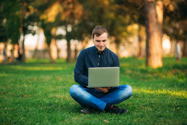 De jonge manager werken op een laptop in het park. Lunchpauze. - Foto, afbeelding