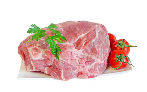 Сырое мясо свинины на белой тарелке, украшенной зеленой петрушкой
 - Фото, изображение