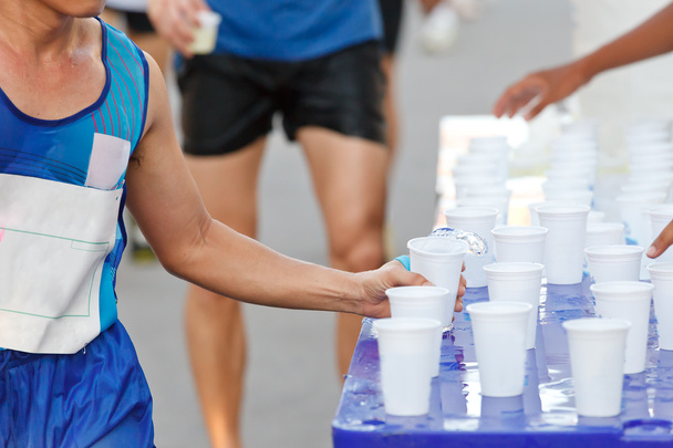 Marathon racer catching cup of water - Photo, Image