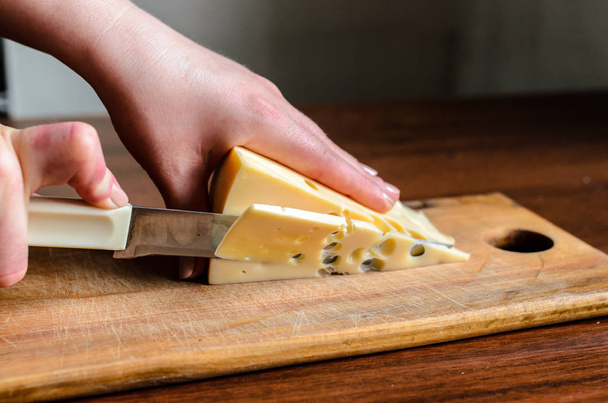 Slicing cheese on a wooden board. - Valokuva, kuva